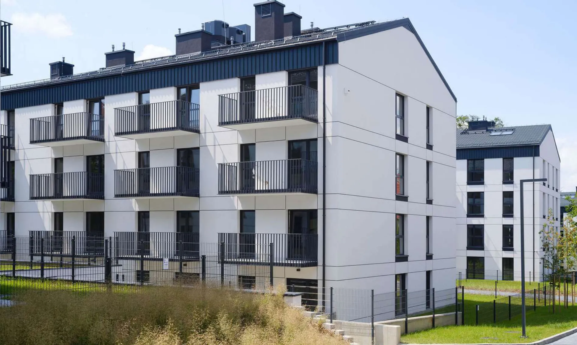 Mehrgeschossiges Mehrfamilienhaus mit durchlaufenden Balkonen und hellem Putz