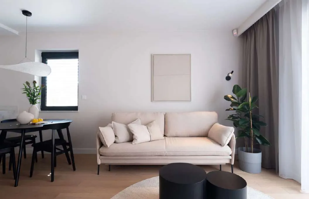 Wohnzimmer mit Sofa, Esstisch und hellem Boden
